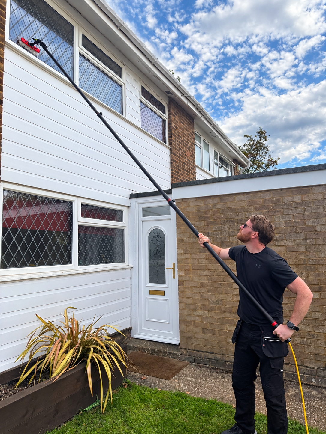 Jack & Sons window cleaner using a reach-and-wash pure water pole on upstairs windows of a home in South Buckinghamshire